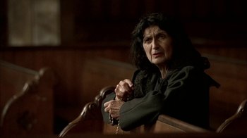 Movie still from “The Sopranos” (1999), created by David Chase – An older woman sitting in a pew with her hands clasped; Close Up shot, High angle