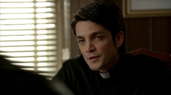 Movie still from “The Sopranos” (1999), created by David Chase – A man wearing a priest's outfit sitting in front of a window; Close Up shot, Over the shoulder angle