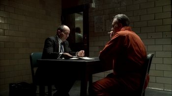 Movie still from “The Sopranos” (1999), created by David Chase – Two men sitting at a table in an interrogation room; Medium shot, Over the shoulder angle