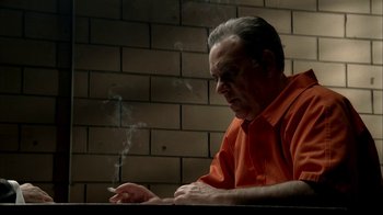 Movie still from “The Sopranos” (1999), created by David Chase – An older man sitting at a table smoking a cigarette; Close Up shot, High angle