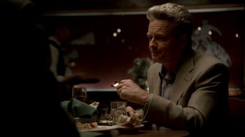 Movie still from “The Sopranos” (1999), created by David Chase – A man sitting at a table with a cigarette in his mouth; Medium shot, Over the shoulder angle