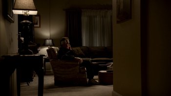 Movie still from “The Sopranos” (1999), created by David Chase – An older man sitting in a chair in a living room; Wide shot, High angle
