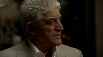 Movie still from “The Sopranos” (1999), created by David Chase – An older man in a white shirt and gray jacket; Close Up shot, Low angle