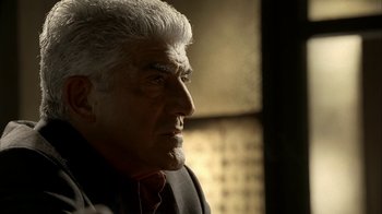 Movie still from “The Sopranos” (1999), created by David Chase – An older man in a suit looking off into the distance; Close Up shot, Over the shoulder angle