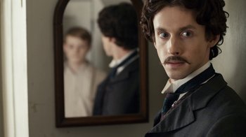Movie still from “Anne with an E” (2017), created by Moira Walley-Beckett – A man with a mustache standing in front of a mirror; Close Up shot, Over the shoulder angle