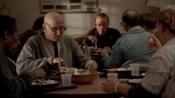 Movie still from “The Sopranos” (1999), created by David Chase – A group of men sitting at a table eating food; Medium shot, Over the shoulder angle