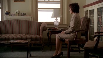 Movie still from “The Sopranos” (1999), created by David Chase – A woman sitting on a chair in a living room next to a lamp; Wide shot, High angle