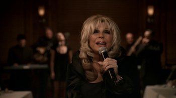 Movie still from “The Sopranos” (1999), created by David Chase – A woman holding a microphone in front of a group of people; Close Up shot, Low angle