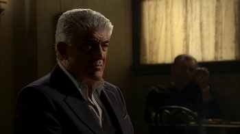 Movie still from “The Sopranos” (1999), created by David Chase – A man in a suit sitting in front of a window; Medium shot, Over the shoulder angle