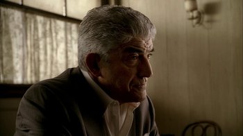 Movie still from “The Sopranos” (1999), created by David Chase – An older man in a suit and tie looking off into the distance; Close Up shot, Low angle