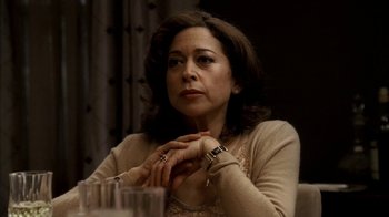 Movie still from “The Sopranos” (1999), created by David Chase – A woman sitting in front of a glass table; Close Up shot, Low angle