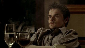 Movie still from “The Sopranos” (1999), created by David Chase – A man sitting in front of a glass of wine; Close Up shot, Low angle