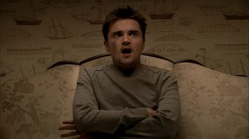 Movie still from “The Sopranos” (1999), created by David Chase – A man sitting in a chair with his arms crossed; Close Up shot, Low angle