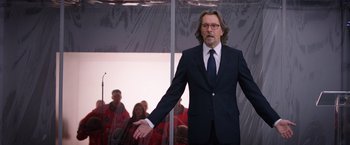 Movie still from “The Space Between Us” (2017), directed by Peter Chelsom – A man wearing a suit and tie standing in front of a group of people; Medium shot, Over the shoulder angle