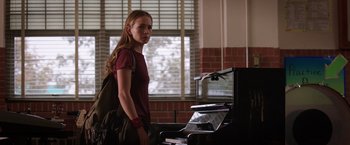 Movie still from “The Space Between Us” (2017), directed by Peter Chelsom – A woman standing in front of an upright piano in a room; Medium shot, Over the shoulder angle
