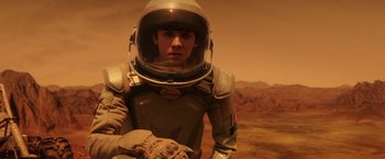 Movie still from “The Space Between Us” (2017), directed by Peter Chelsom – A man in a space suit is standing in front of a wall; Medium shot, Over the shoulder angle