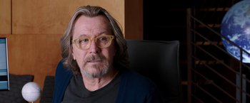 Movie still from “The Space Between Us” (2017), directed by Peter Chelsom – A person wearing glasses sitting in a chair; Close Up shot, Over the shoulder angle