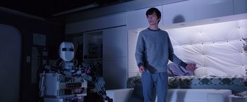 Movie still from “The Space Between Us” (2017), directed by Peter Chelsom – A man holding a knife in a room with a robot; Medium shot, Low angle