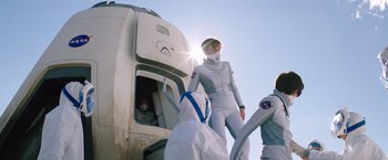 Movie still from “The Space Between Us” (2017), directed by Peter Chelsom – A person in a spacesuit is standing in front of a space ship; Medium shot, Over the shoulder angle