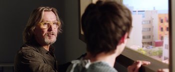 Movie still from “The Space Between Us” (2017), directed by Peter Chelsom – A man with glasses is looking into a mirror; Close Up shot, Over the shoulder angle