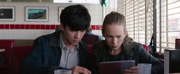 Movie still from “The Space Between Us” (2017), directed by Peter Chelsom – A man and a woman sitting at a table looking at an ipad; Close Up shot, High angle