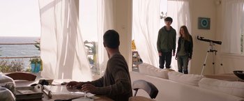 Movie still from “The Space Between Us” (2017), directed by Peter Chelsom – A man sitting at a table with a computer in front of him; Wide shot, Over the shoulder angle