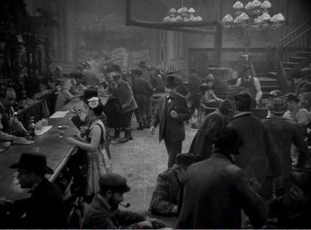 Movie still from “The Spoilers” (1942), directed by Ray Enright – A group of people gathered in an old fashion setting; Wide shot, High angle