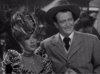 Movie still from “The Spoilers” (1942), directed by Ray Enright – A man and a woman standing next to each other; Medium shot, Low angle