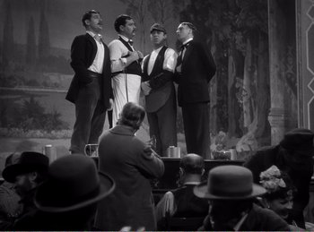 Movie still from “The Spoilers” (1942), directed by Ray Enright – A group of men standing next to each other on a stage; Wide shot, High angle