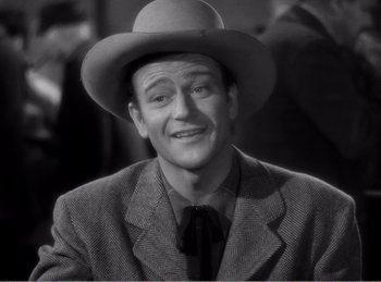 Movie still from “The Spoilers” (1942), directed by Ray Enright – A man wearing a hat and a suit; Close Up shot, Low angle