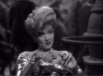Movie still from “The Spoilers” (1942), directed by Ray Enright – An old black and white photo of a woman in a gold dress; Close Up shot, Over the shoulder angle