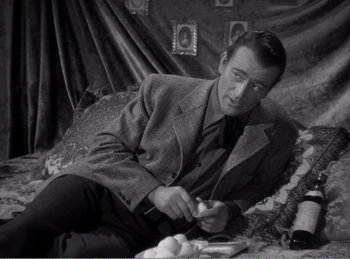 Movie still from “The Spoilers” (1942), directed by Ray Enright – A black and white photo of a man sitting on the floor; Medium shot, High angle