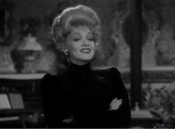 Movie still from “The Spoilers” (1942), directed by Ray Enright – A black and white photo of a woman in a black dress; Close Up shot, Over the shoulder angle