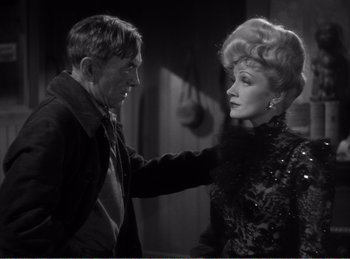 Movie still from “The Spoilers” (1942), directed by Ray Enright – An old photo of a man and a woman; Medium shot, Over the shoulder angle