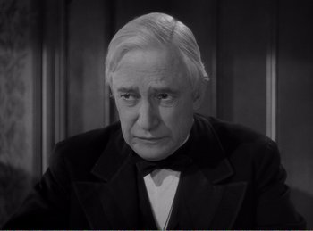 Movie still from “The Spoilers” (1942), directed by Ray Enright – An older man wearing a suit and bow tie; Close Up shot, High angle
