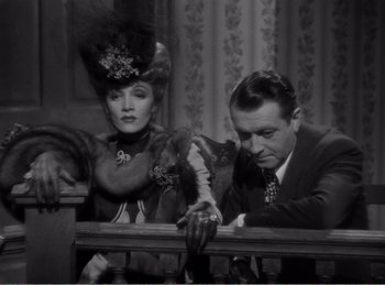 Movie still from “The Spoilers” (1942), directed by Ray Enright – A man and a woman sitting next to a railing; Medium shot, Low angle