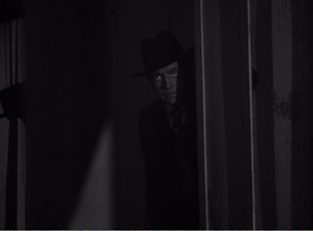 Movie still from “The Spoilers” (1942), directed by Ray Enright – A man wearing a hat and a tie; Medium shot, High angle
