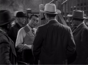 Movie still from “The Spoilers” (1942), directed by Ray Enright – A group of men standing next to each other; Medium shot, High angle
