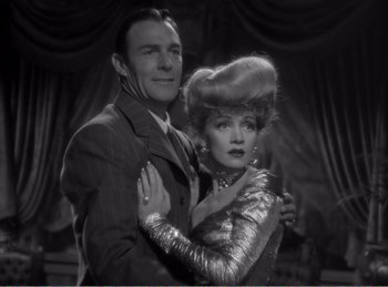 Movie still from “The Spoilers” (1942), directed by Ray Enright – A man and a woman are posing for a picture; Medium shot, Low angle