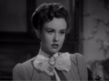 Movie still from “The Spoilers” (1942), directed by Ray Enright – A woman in a dress and a white bow tie; Close Up shot, Over the shoulder angle