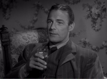 Movie still from “The Spoilers” (1942), directed by Ray Enright – A black and white photo of a man holding a glass of wine; Close Up shot, High angle