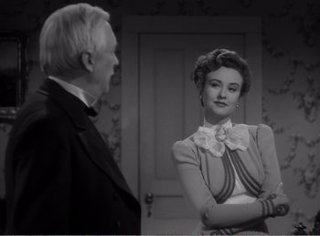 Movie still from “The Spoilers” (1942), directed by Ray Enright – An older man standing next to an older woman in front of a door; Medium shot, Over the shoulder angle