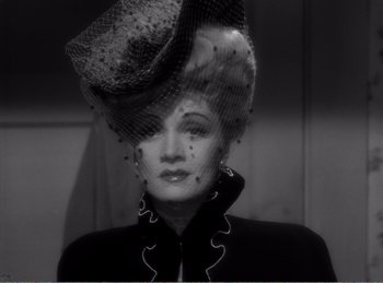 Movie still from “The Spoilers” (1942), directed by Ray Enright – A black and white photo of a woman wearing a hat; Close Up shot, Low angle