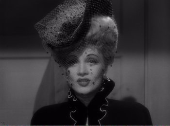 Movie still from “The Spoilers” (1942), directed by Ray Enright – A black and white photo of a woman wearing a hat; Close Up shot, Low angle