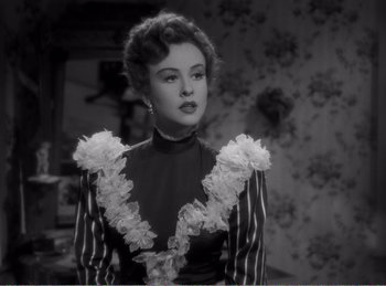 Movie still from “The Spoilers” (1942), directed by Ray Enright – A black and white photo of a woman in a dress; Close Up shot, Over the shoulder angle