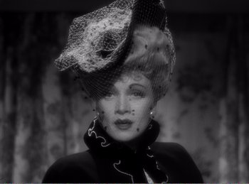 Movie still from “The Spoilers” (1942), directed by Ray Enright – A black and white photo of a woman wearing a hat; Close Up shot, Low angle