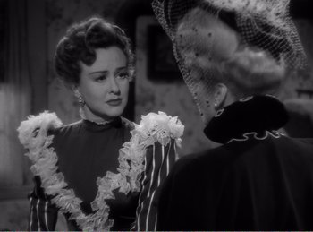 Movie still from “The Spoilers” (1942), directed by Ray Enright – A woman in a black and white photo talking to another woman in a black and white photo; Close Up shot, Over the shoulder angle