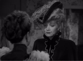 Movie still from “The Spoilers” (1942), directed by Ray Enright – A woman wearing a hat with a veil on top of her head; Close Up shot, Over the shoulder angle