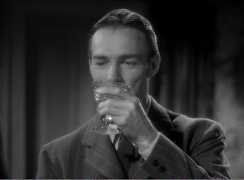 Movie still from “The Spoilers” (1942), directed by Ray Enright – A black and white photo of a man drinking a glass; Close Up shot, High angle