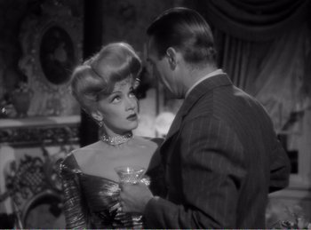 Movie still from “The Spoilers” (1942), directed by Ray Enright – A man and a woman standing next to each other in a room; Close Up shot, Over the shoulder angle